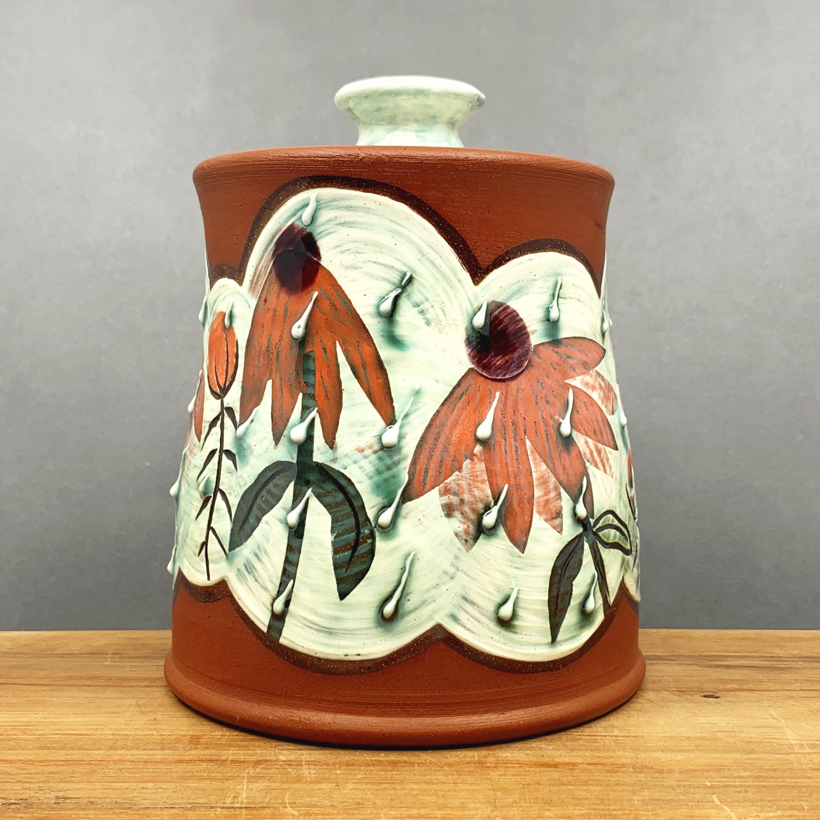 Handmade ceramic jar with lid by NC pottery Amy Irish. Jar is decorated with coneflowers. Available at larkandkey.com, Charlotte NC.