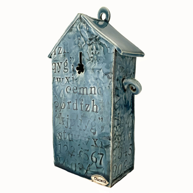 Handmade ceramic house by artist Barbara Chadwick, blue with white dogwood flowers, letter and number details. Back view.