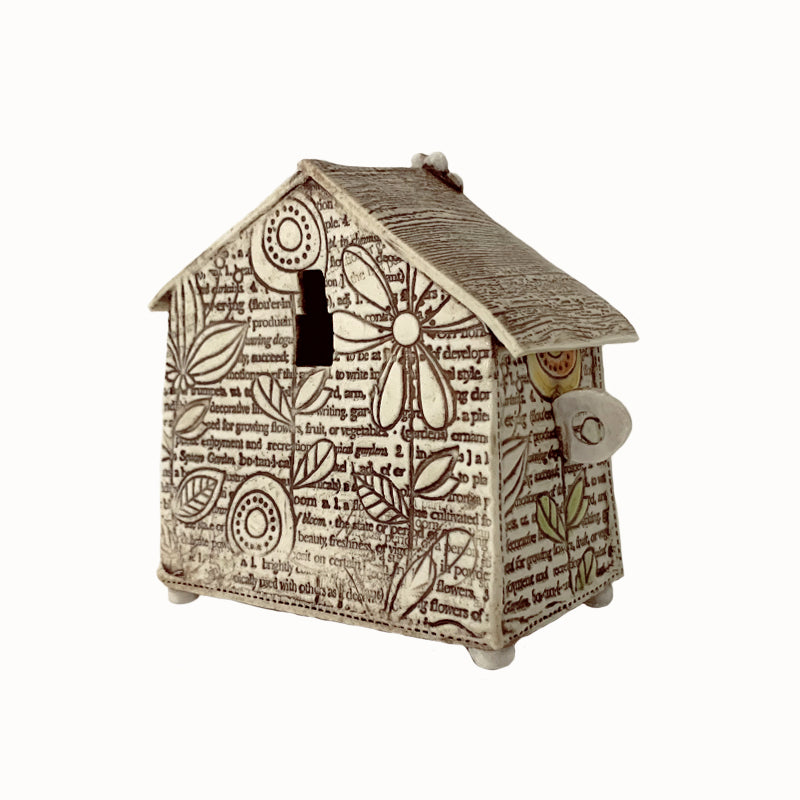 Handmade porcelain house by ceramic artist Barbara Chadwick, flower and botanical definitions create a background texture with orange flowers on top. Back view.