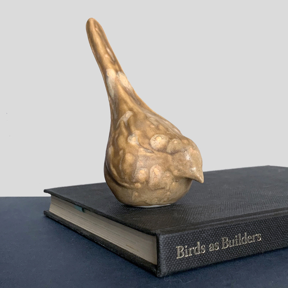Small, hand sculpted ceramic bird glazed in a light brown, butterscotch color by artist Becky Story.