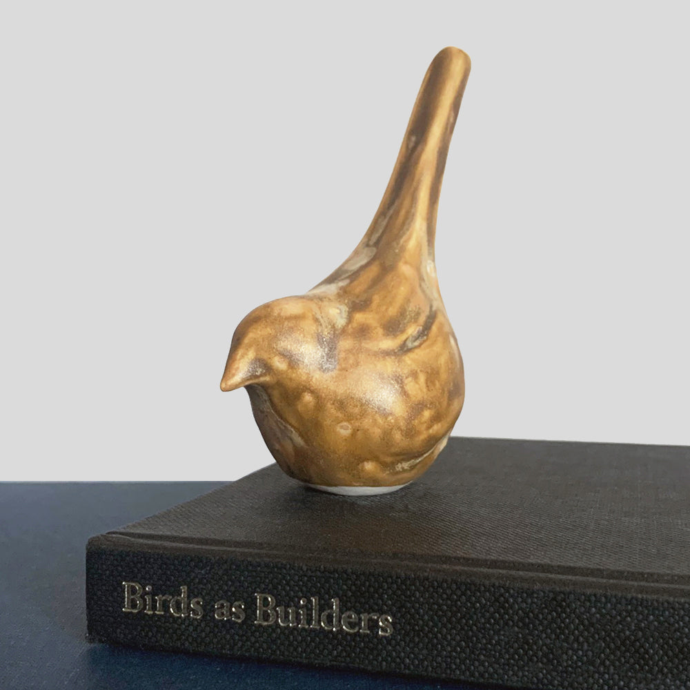 Small, hand sculpted ceramic bird glazed in a light brown, butterscotch color by artist Becky Story.