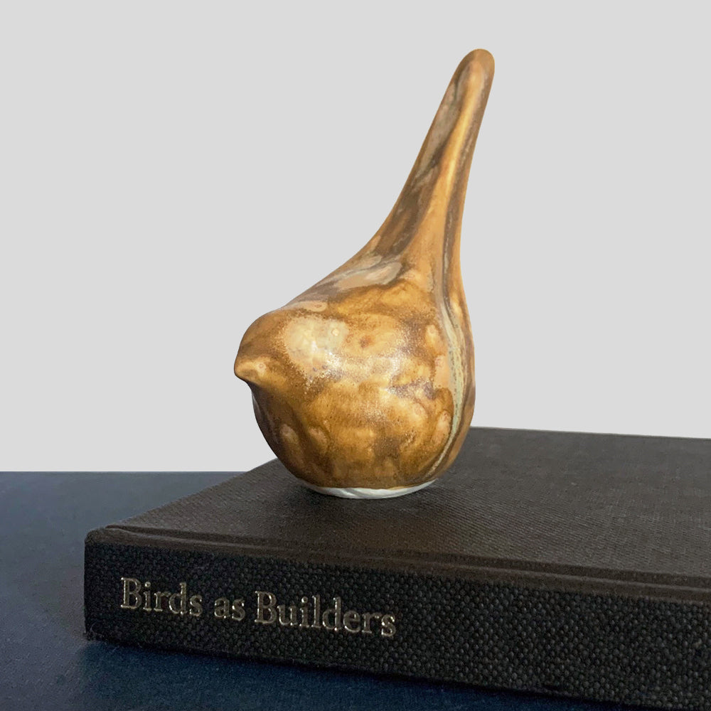 Small, hand sculpted ceramic bird glazed in a light brown, butterscotch color by artist Becky Story.