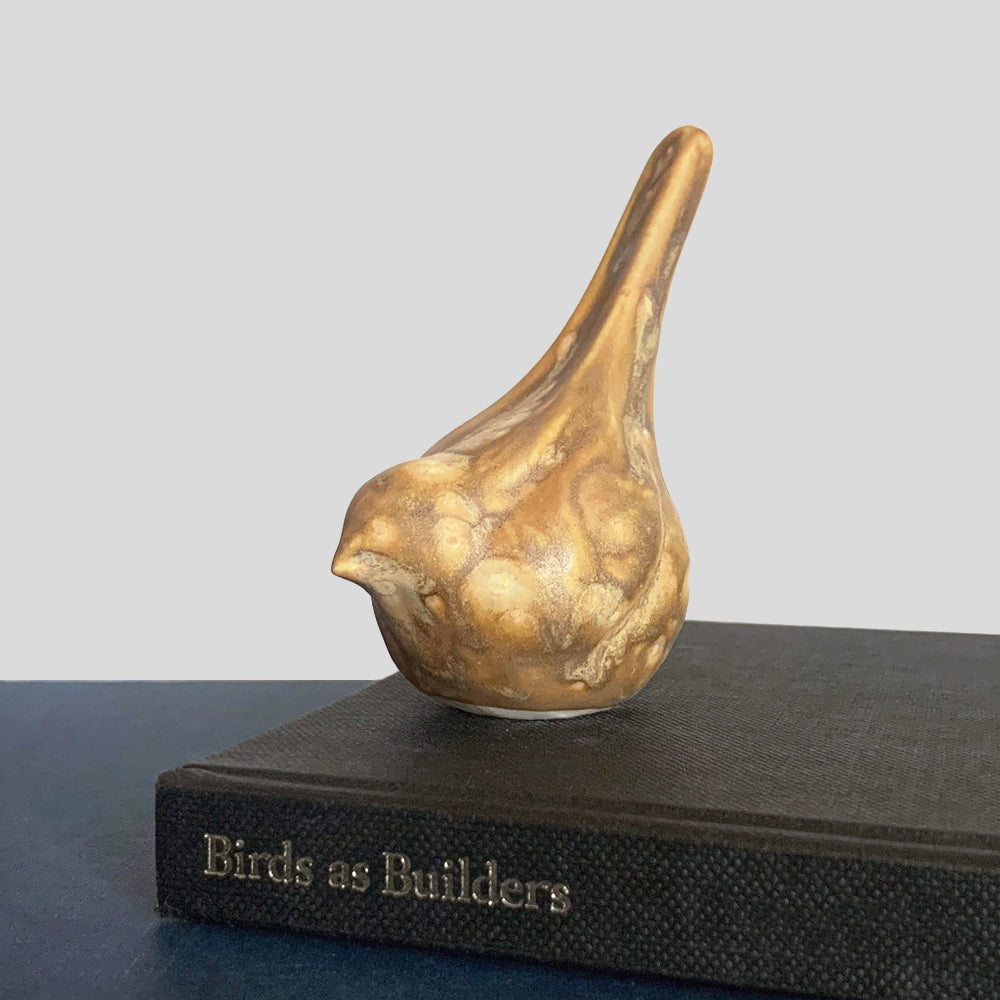 Small, hand sculpted ceramic bird glazed in a light brown, butterscotch color by artist Becky Story.