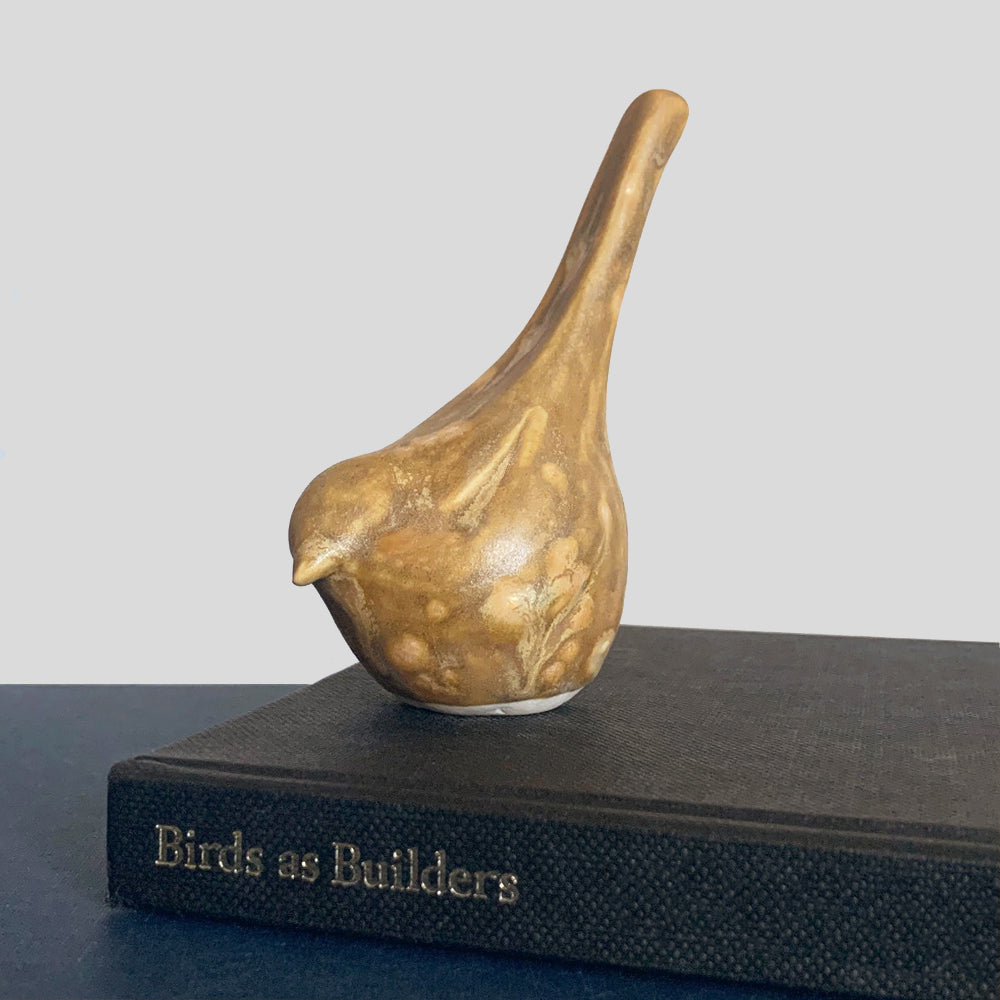 Small, hand sculpted ceramic bird glazed in a light brown, butterscotch color by artist Becky Story.