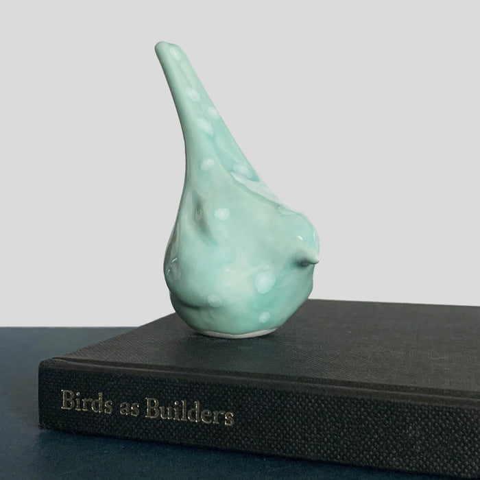 Small ceramic sculpture of a bird, glazed in an aqua blue crystalline glaze, by artist Becky Story.