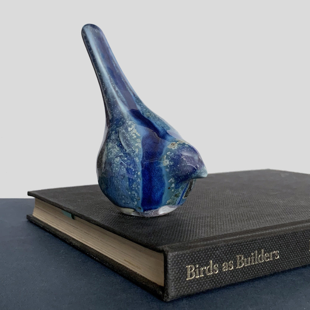 Small, hand sculpted ceramic bird glazed in shiny blues by artist Becky Story.