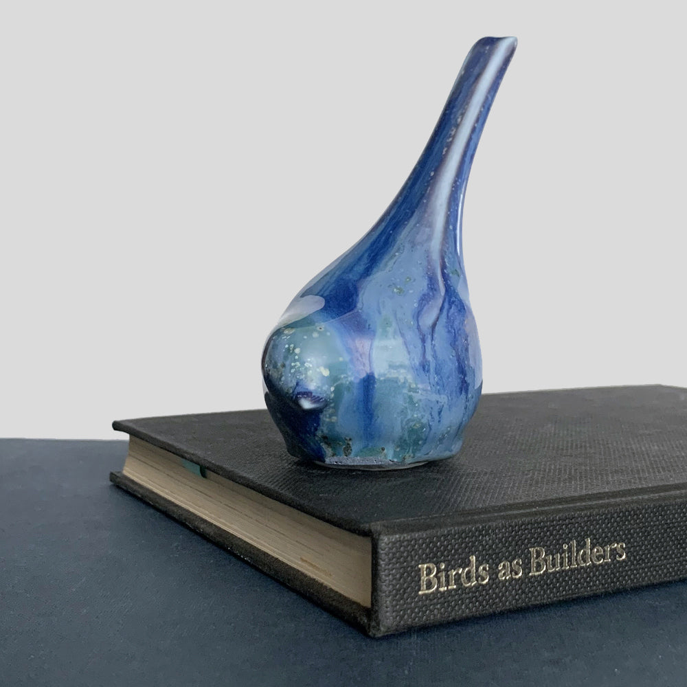 Small, hand sculpted ceramic bird glazed in shiny blues by artist Becky Story.