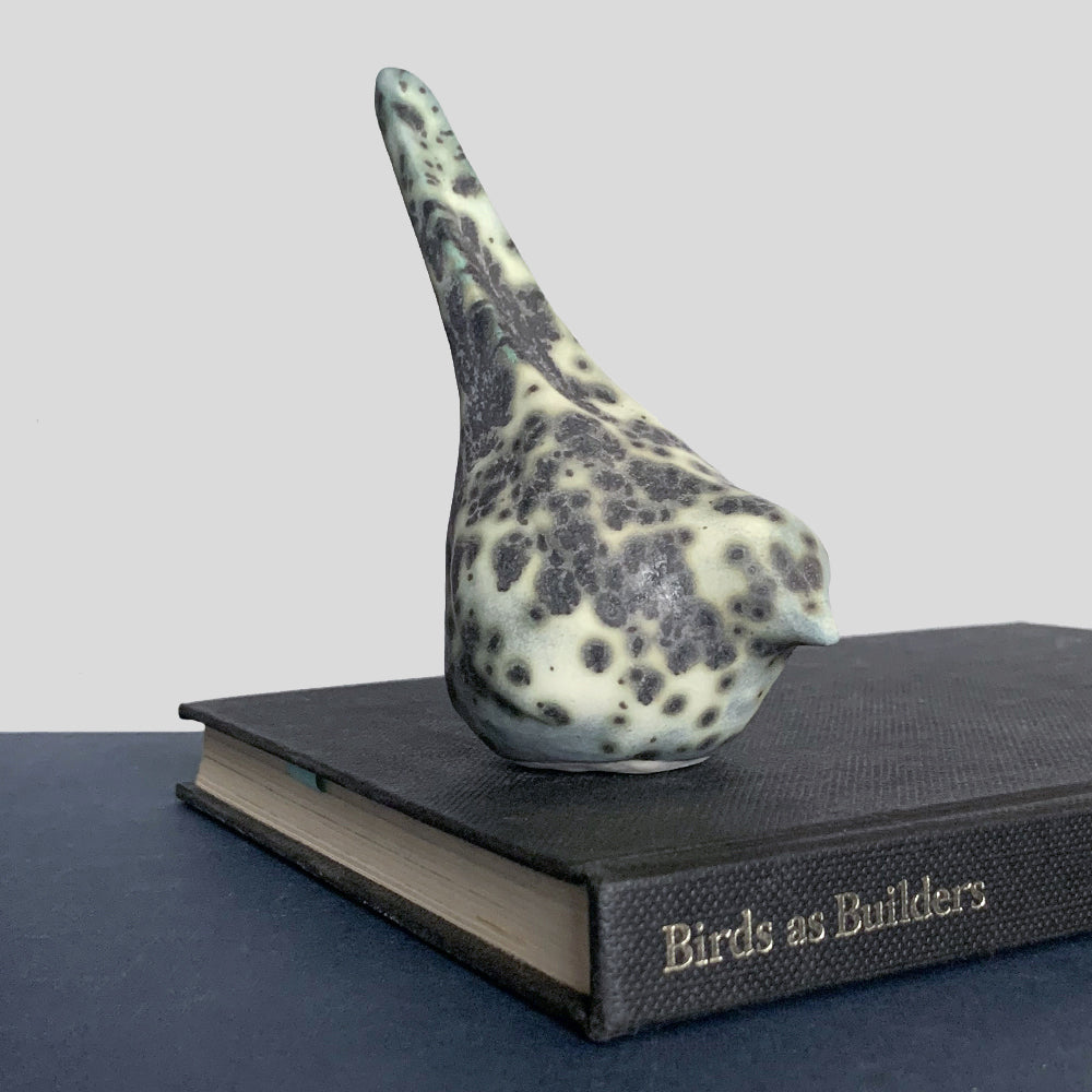 Small, hand sculpted ceramic bird glazed in a cream, pale bluish green and dark gray color by artist Becky Story.