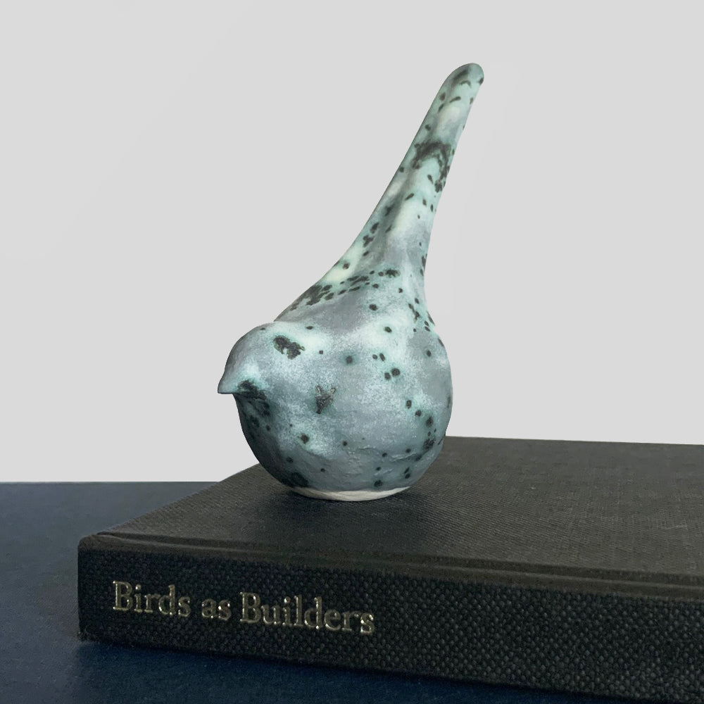 Small, hand sculpted ceramic bird glazed in a cream, pale bluish green and dark gray color by artist Becky Story.
