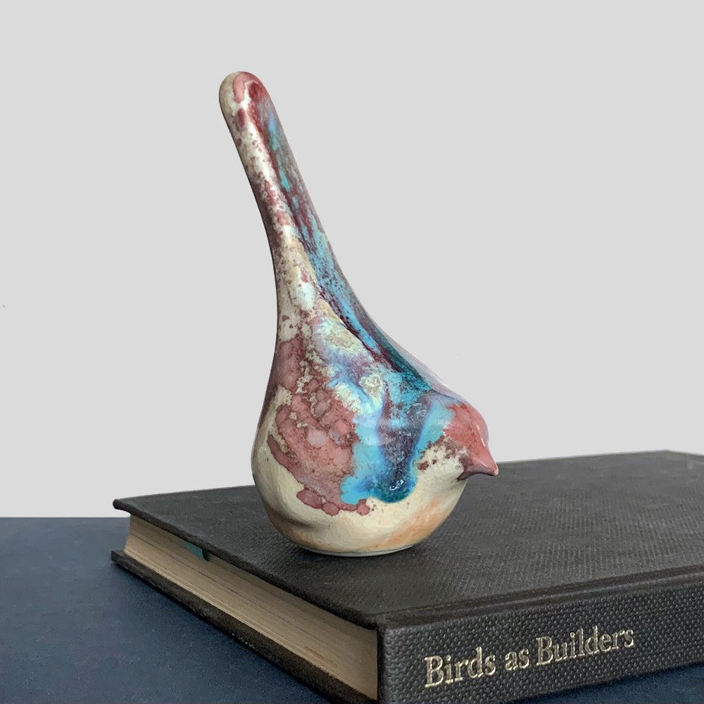Small ceramic sculpture of a bird, glazed in a rust, cream and blue glaze by artist Becky Story.