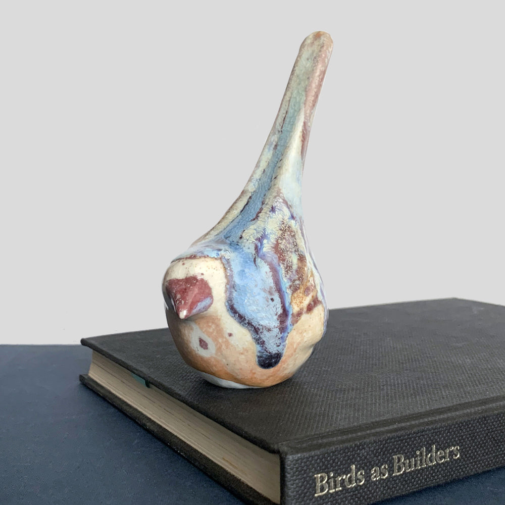 Small ceramic sculpture of a bird, glazed in a rust, cream and blue glaze by artist Becky Story.