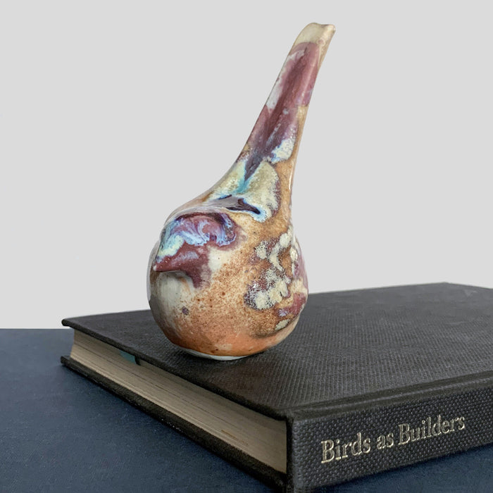 Small ceramic sculpture of a bird, glazed in a rust, cream and blue glaze by artist Becky Story.
