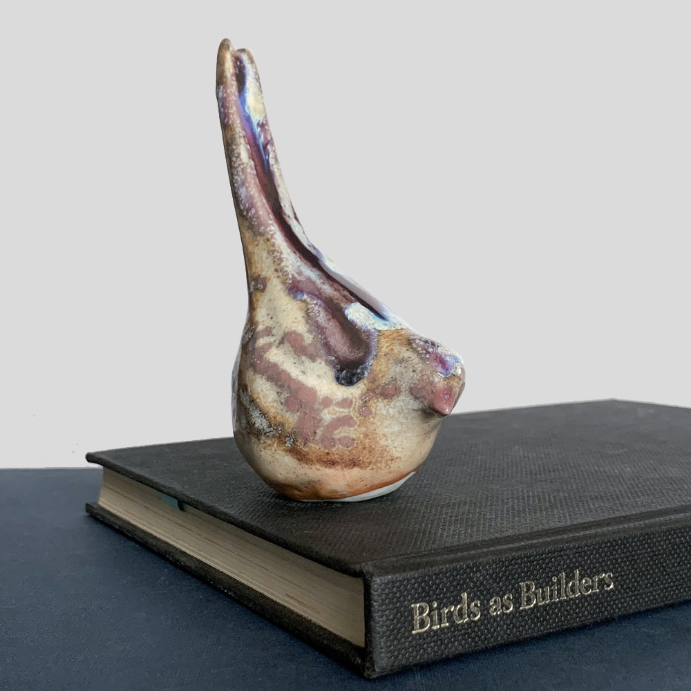 Small ceramic sculpture of a bird, glazed in a rust, cream and blue glaze by artist Becky Story.