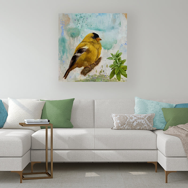 "Radiant Sky" painting by Eleanor Miller. A large yellow goldfinch perched on a branch, with colorful watercolor background. Shown in a living room scene over a sofa.