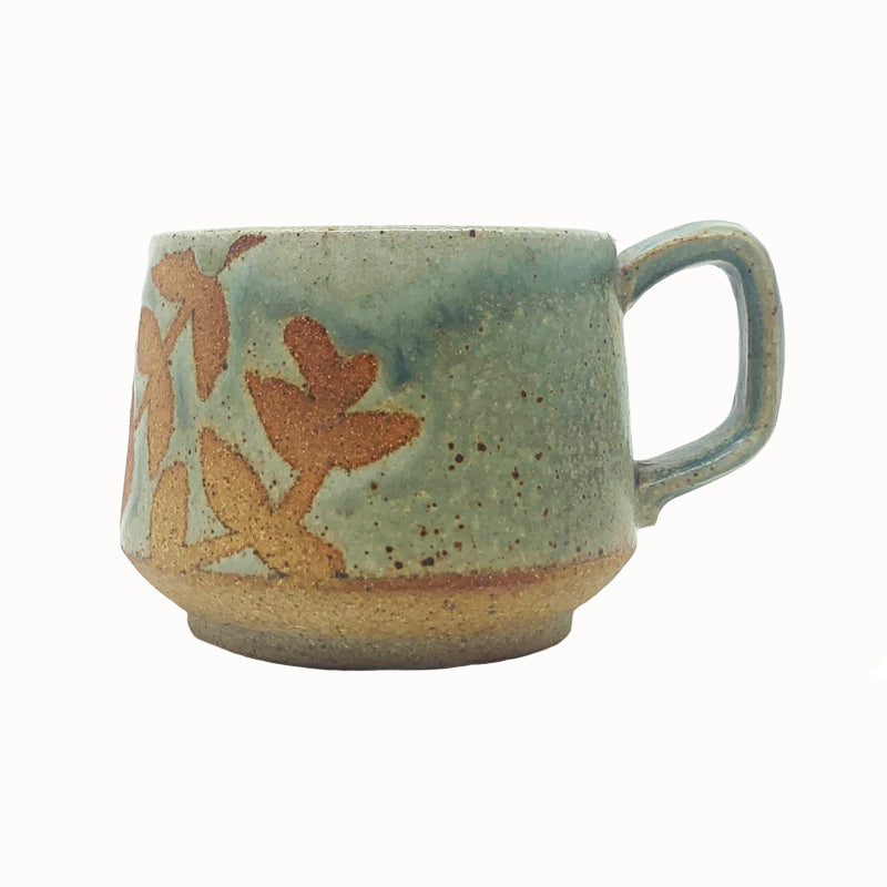 Heather Ossandon handmade, woodfired mug, side view. Light green with rusty botanical pattern.