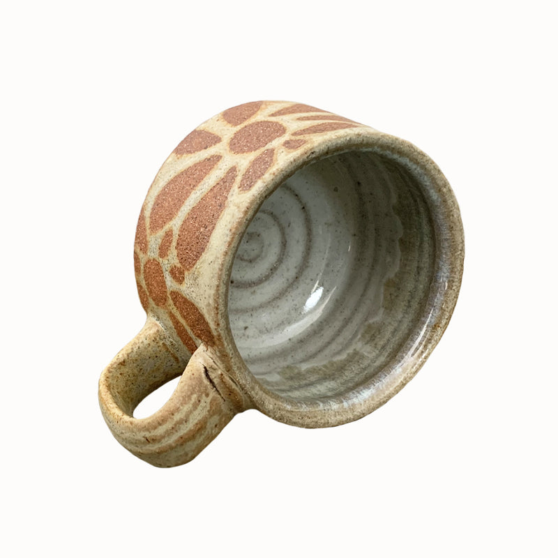 Heather Ossandon handmade, woodfired mug, side view. Creamy hues with rust flower pattern.