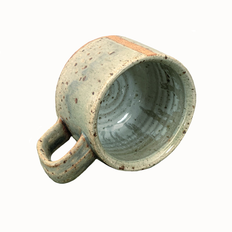 Heather Ossandon handmade, woodfired mug, angled view. Light green with rusty stripes.