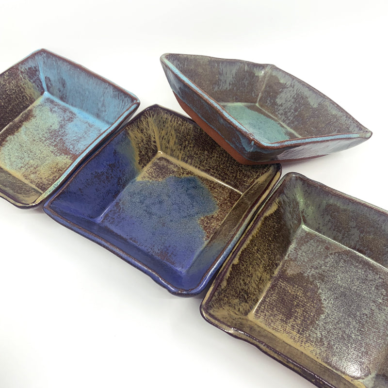 Small, multicolor square bowls by potter Jim Rientjes. Earthy tones and vibrant blues.
