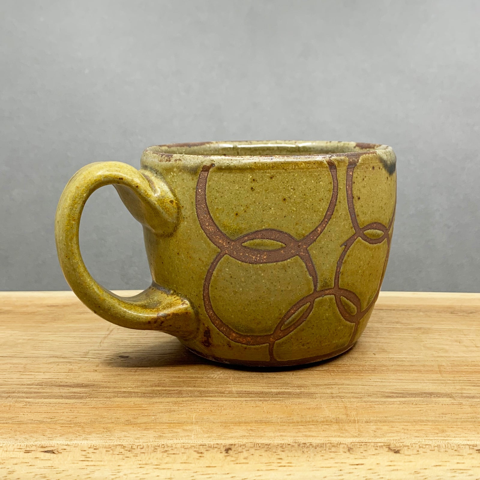 Handmade stoneware mug with golden yellow glaze and rusty circles pattern by Western NC potter Julie Covington. Available at larkandkey.com, Charlotte NC.