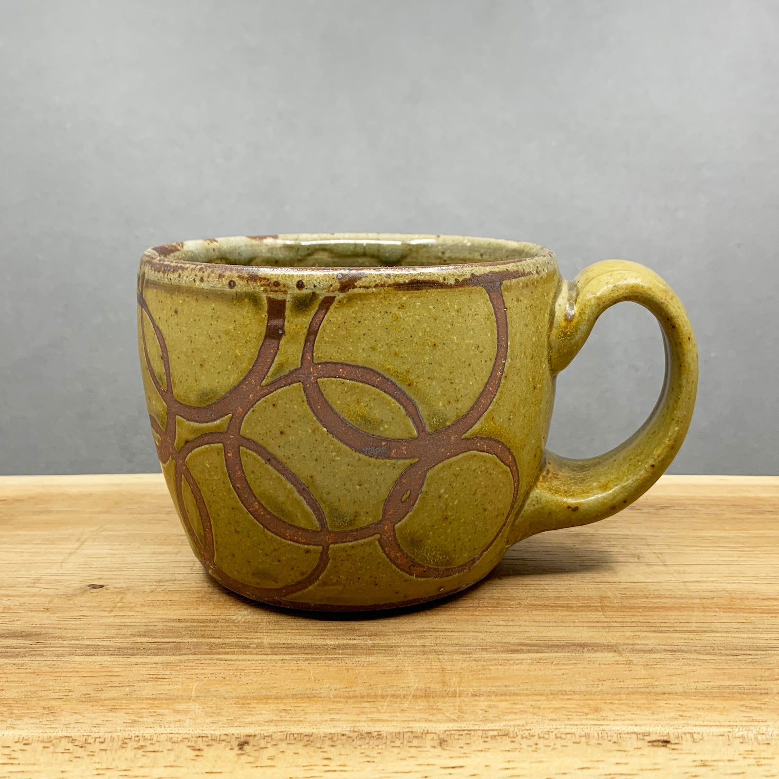 Handmade stoneware mug with golden yellow glaze and rusty circles pattern by Western NC potter Julie Covington. Available at larkandkey.com, Charlotte NC.