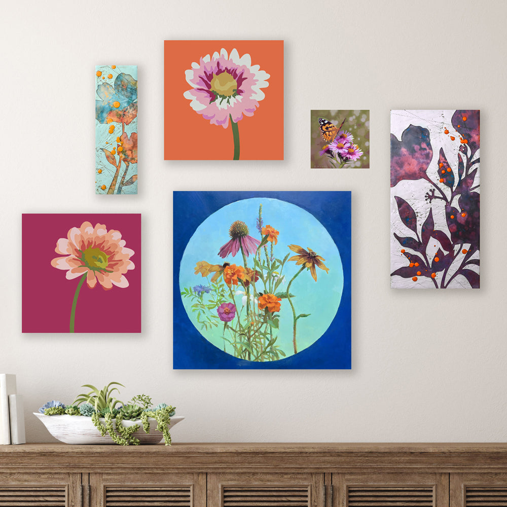Various  multi-size paintings grouped on a wall. Artwork from Michele Aschenbrenner, Sarah Treanor, Sarah Moore and Wendy Rouse.  The paintings are a mix of flowers, mediums and styles - showcased in a colorful display.
