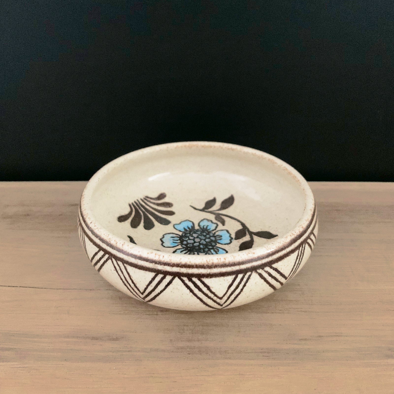 Handmade pottery from Off Menu Pots. Small round catchall dish with blue flower, handmade. Side view.