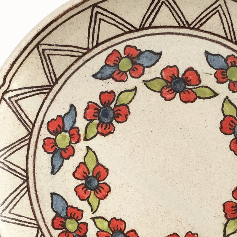 Handmade pottery from Off Menu Pots. Dessert plate with blue, red and chartreuse flowers. Detail.