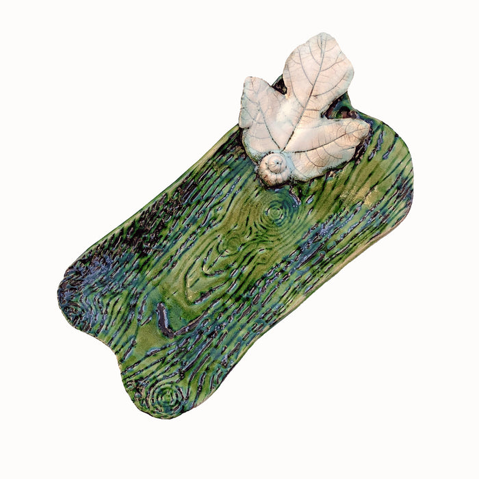 Handmade dish by ceramic artist Paula Smith. Small rectangular tray with curvy ends, green body with woodgrain detail accented with white fig leaf.