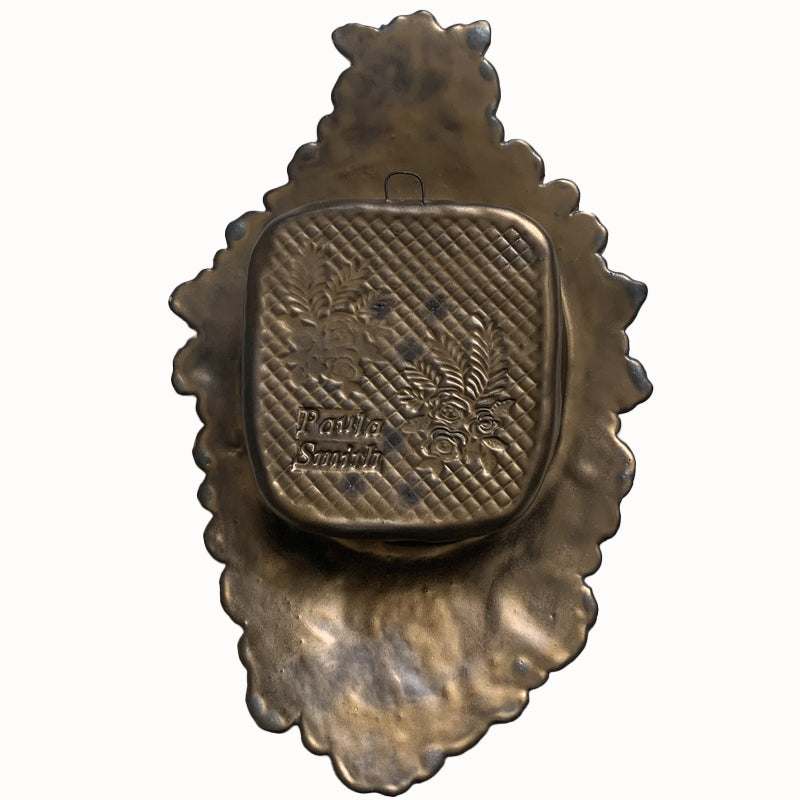 Handmade ceramic wall niche by Paula Smith. Clay face is stamped with flower patterns and an elephant, finished in a gunmetal glaze. There are three dimensional  orange flowers. Back view for hanging.