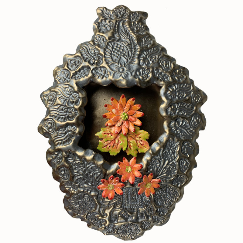 Handmade ceramic wall niche by Paula Smith. Clay face is stamped with flower patterns and an elephant, finished in a gunmetal glaze. There are three dimensional  orange flowers.