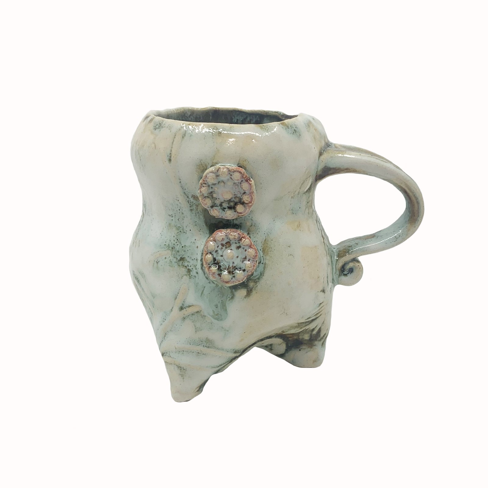 Handmade ceramic cup by artist Paula Smith. Curvy cup with handle, creamy white  body with floral detail, decorated with two pink buttons.