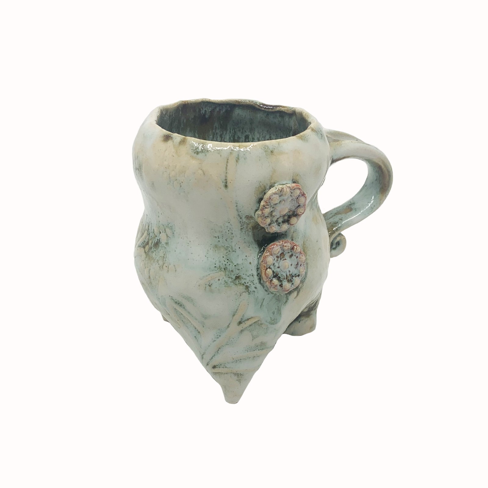 Handmade ceramic cup by artist Paula Smith. Curvy cup with handle, creamy white  body with floral detail, decorated with two pink buttons.