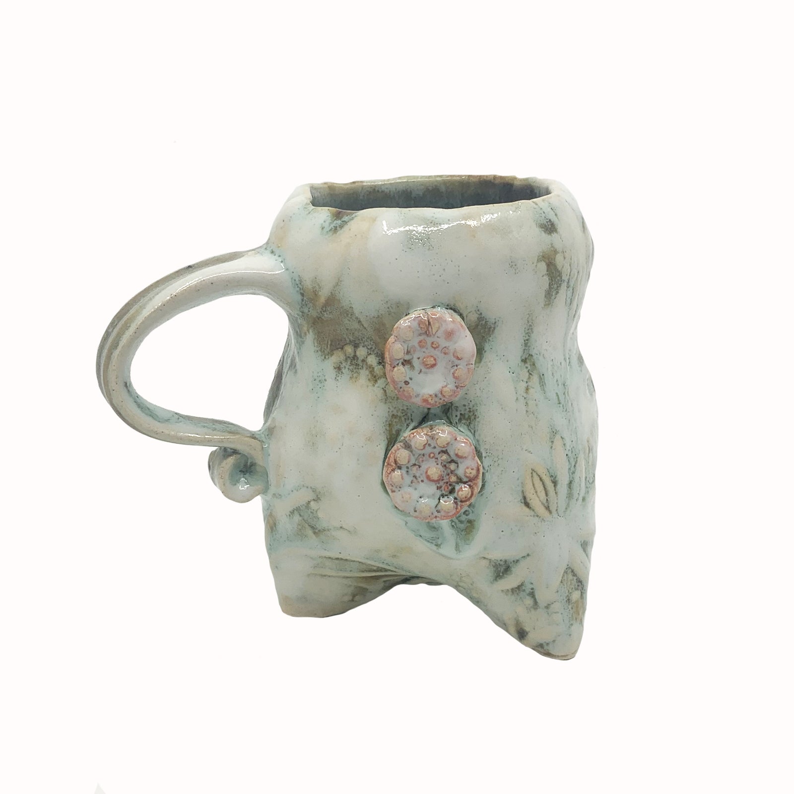 Handmade ceramic cup by artist Paula Smith. Curvy cup with handle, creamy white  body with floral detail, decorated with pink buttons.