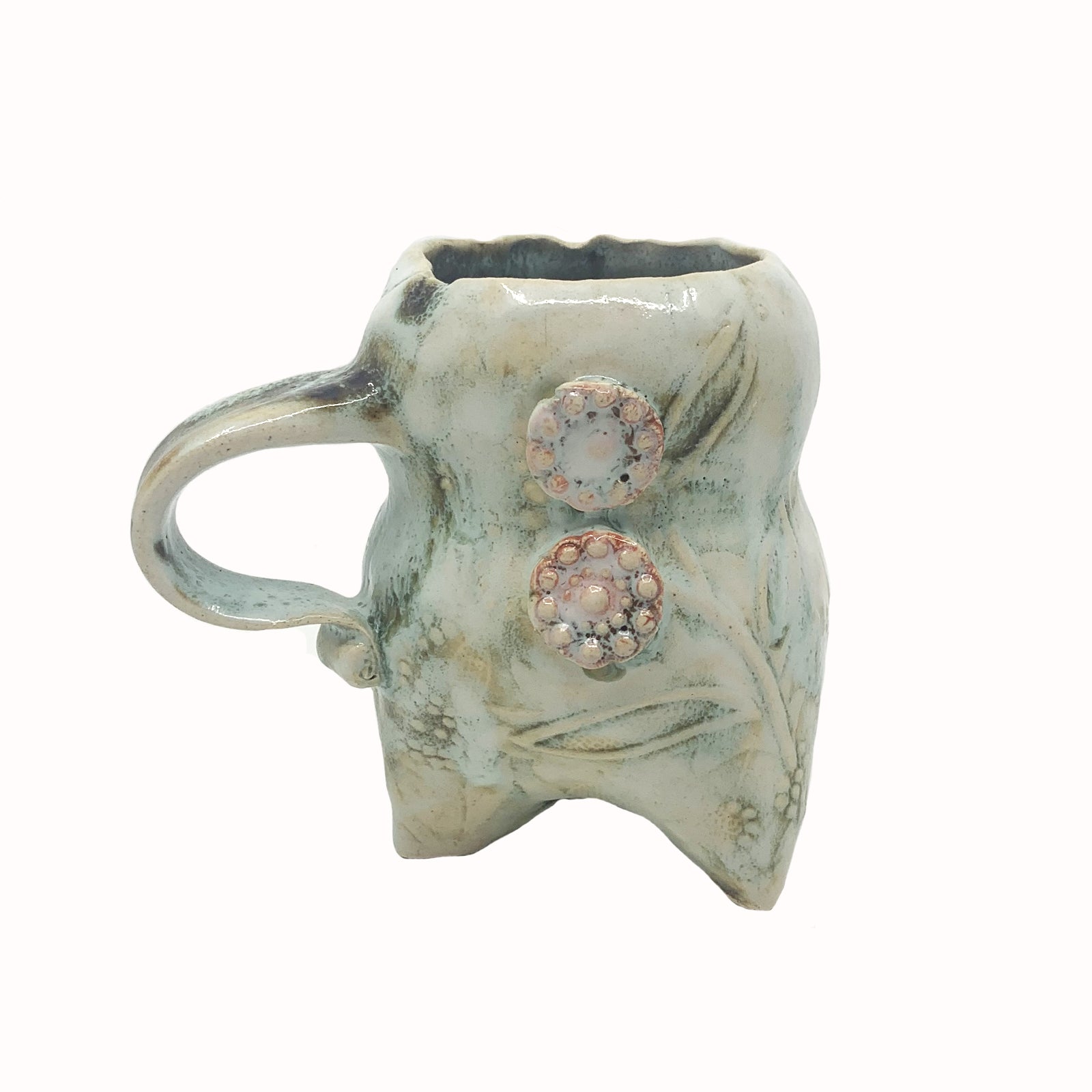 Handmade ceramic cup by artist Paula Smith. Curvy cup with handle, creamy white  body with floral detail, decorated with pink buttons. View 2.