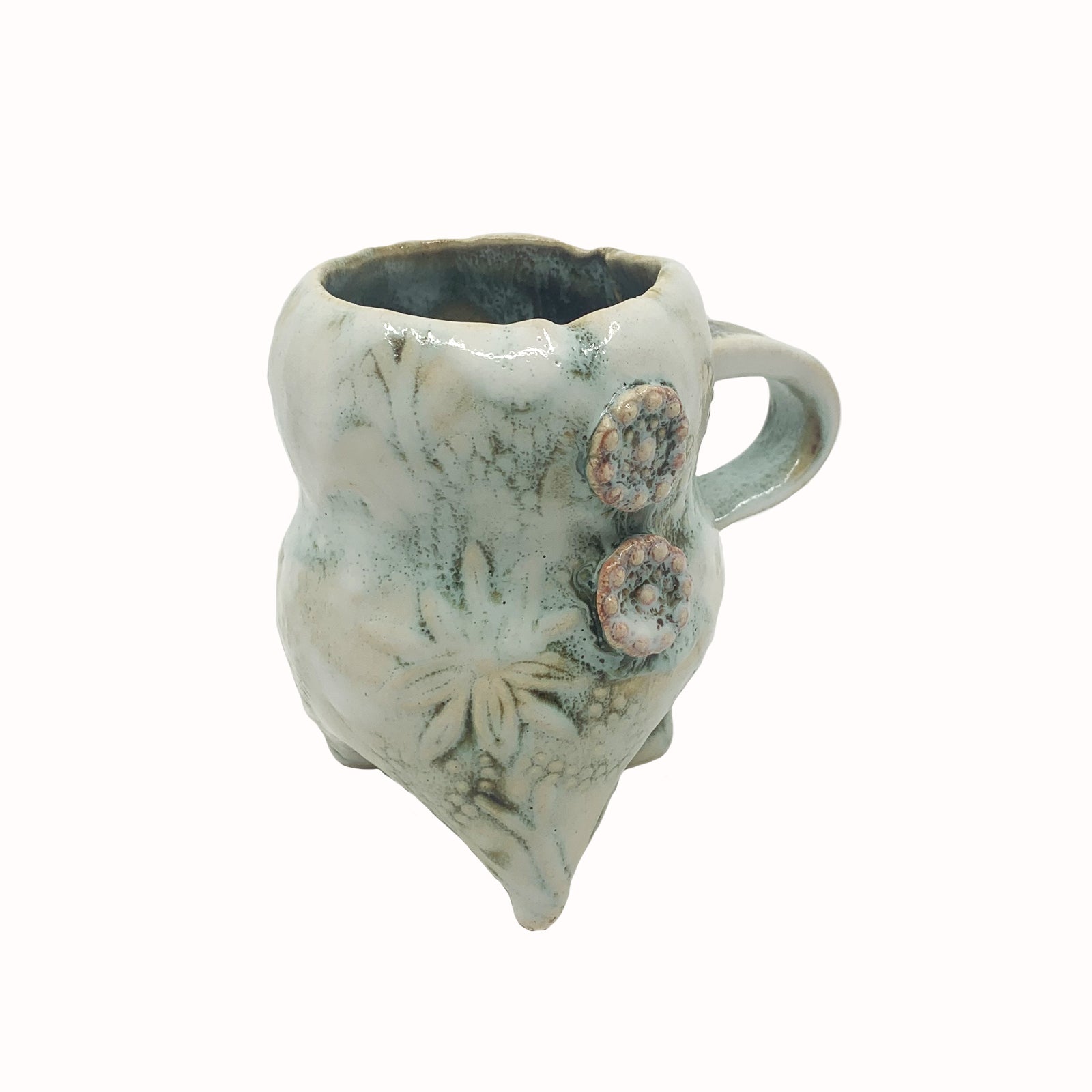 Handmade ceramic cup by artist Paula Smith. Curvy cup with handle, creamy white  body with floral detail, decorated with pink buttons. View 2.