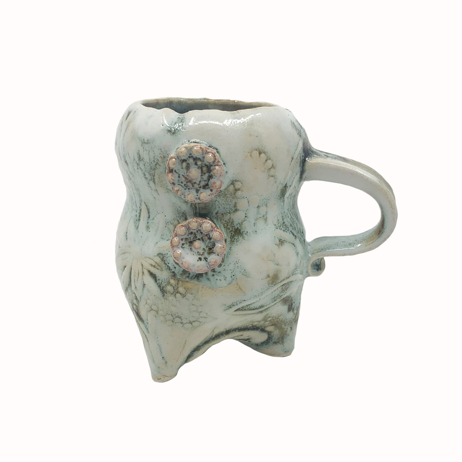 Handmade ceramic cup by artist Paula Smith. Curvy cup with handle, creamy white  body with floral detail, decorated with pink buttons.
