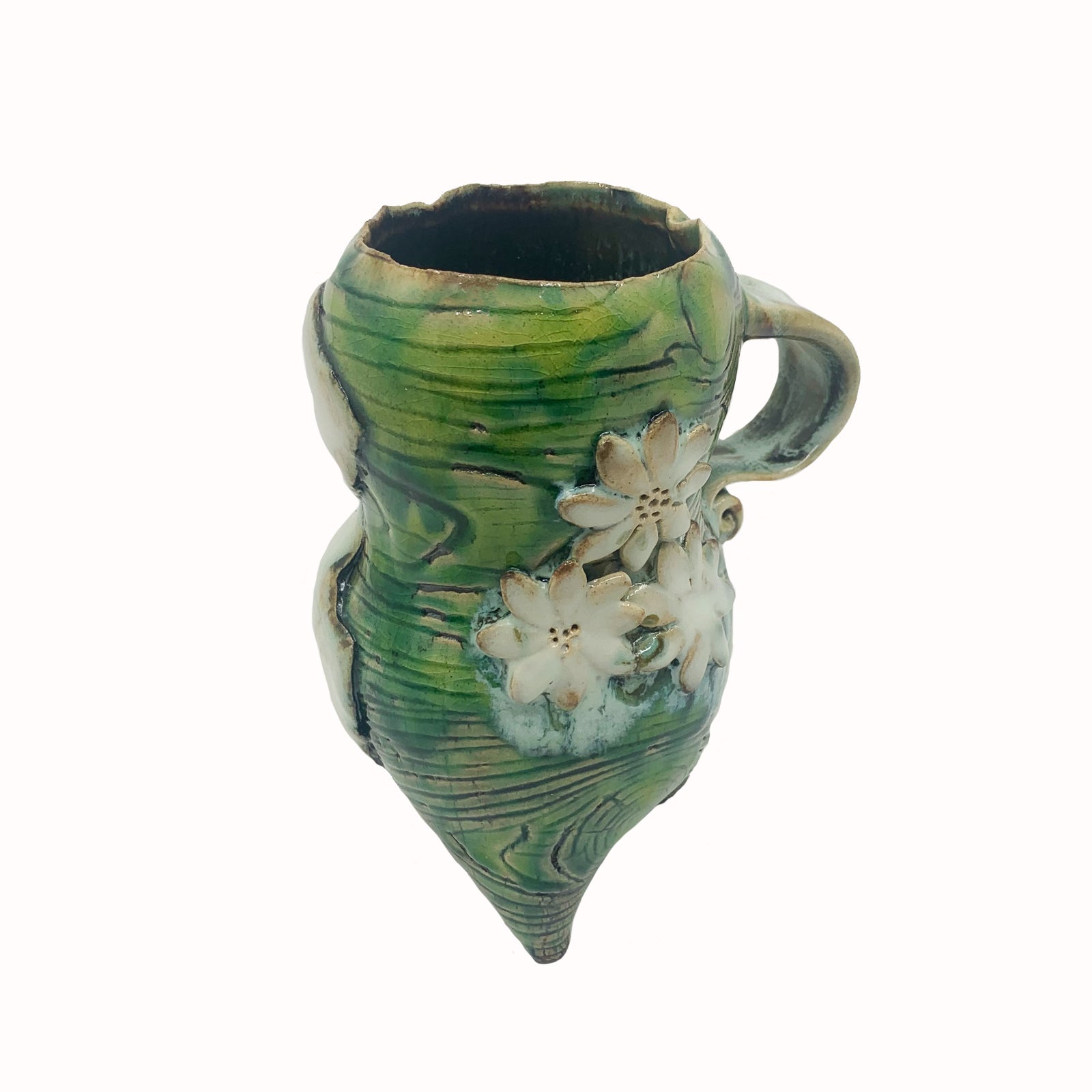 Handmade ceramic cup by artist Paula Smith. Curvy cup with handle, green body with woodgrain detail, decorated with white flowers and white fig leaf on opposite side. Top angled view.