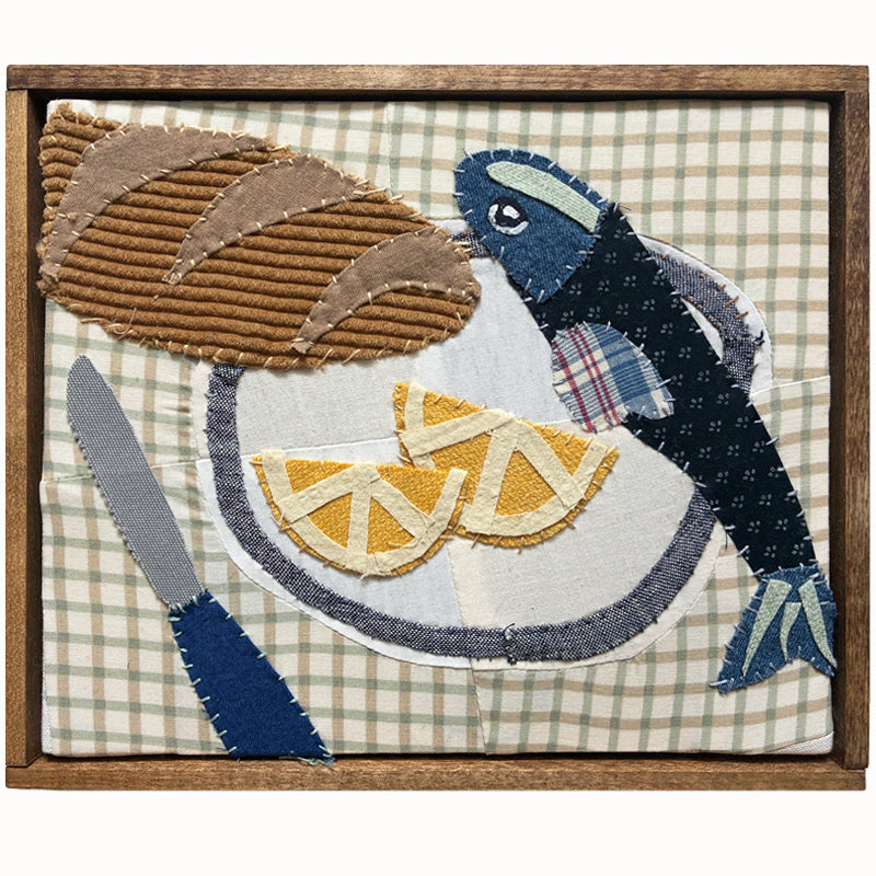 Veggie Plate textile collage by artist Hannah Goff. The artwork is comprised of hand-sewn, reclaimed and recycled fabrics, and features an anchovy, bread, lemon wedges and knife. Finished in a handmade rustic wood frame.