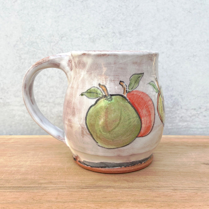 Handmade ceramic mug by NC potter Molly Lithgo. White with red and green apple decoration. 