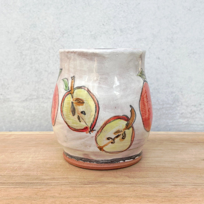 Handmade ceramic mug by NC potter Molly Lithgo. White with red and green apple decoration. View two, showing a an apple cut open.
