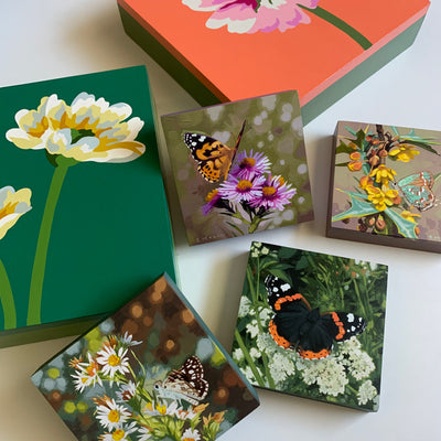A collection of colorful flower and butterfly paintings by Michele Aschenbrenner and Sarah Moore.