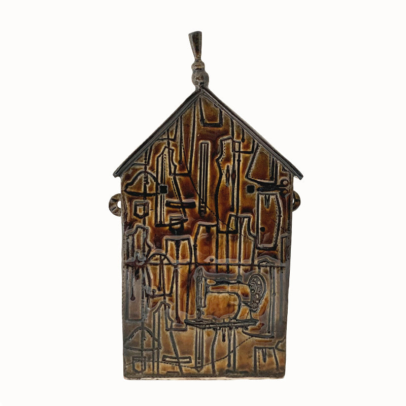Handmade ceramic house by artist Barbara Chadwick, brown with sewing pattern, sewing machine, scissor and thread details.