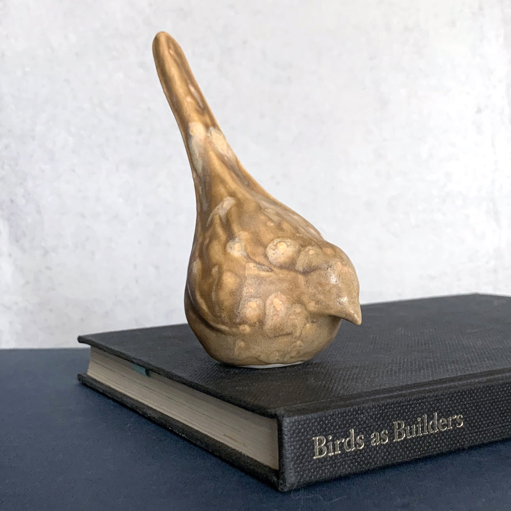 Small, hand sculpted ceramic bird glazed in a light brown, butterscotch color by artist Becky Story. 