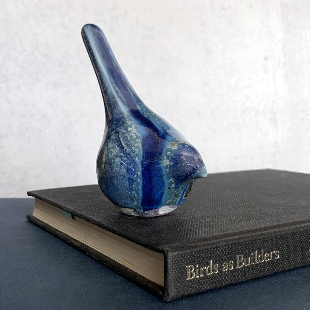 Small, hand sculpted ceramic bird glazed in shiny blues by artist Becky Story. 