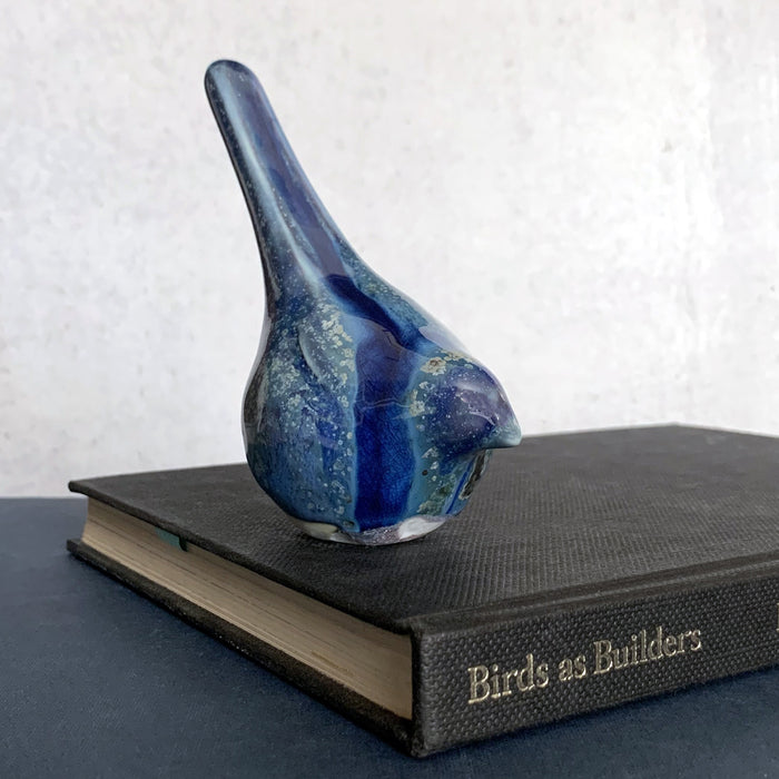 Small, hand sculpted ceramic bird glazed in shiny blues by artist Becky Story. 