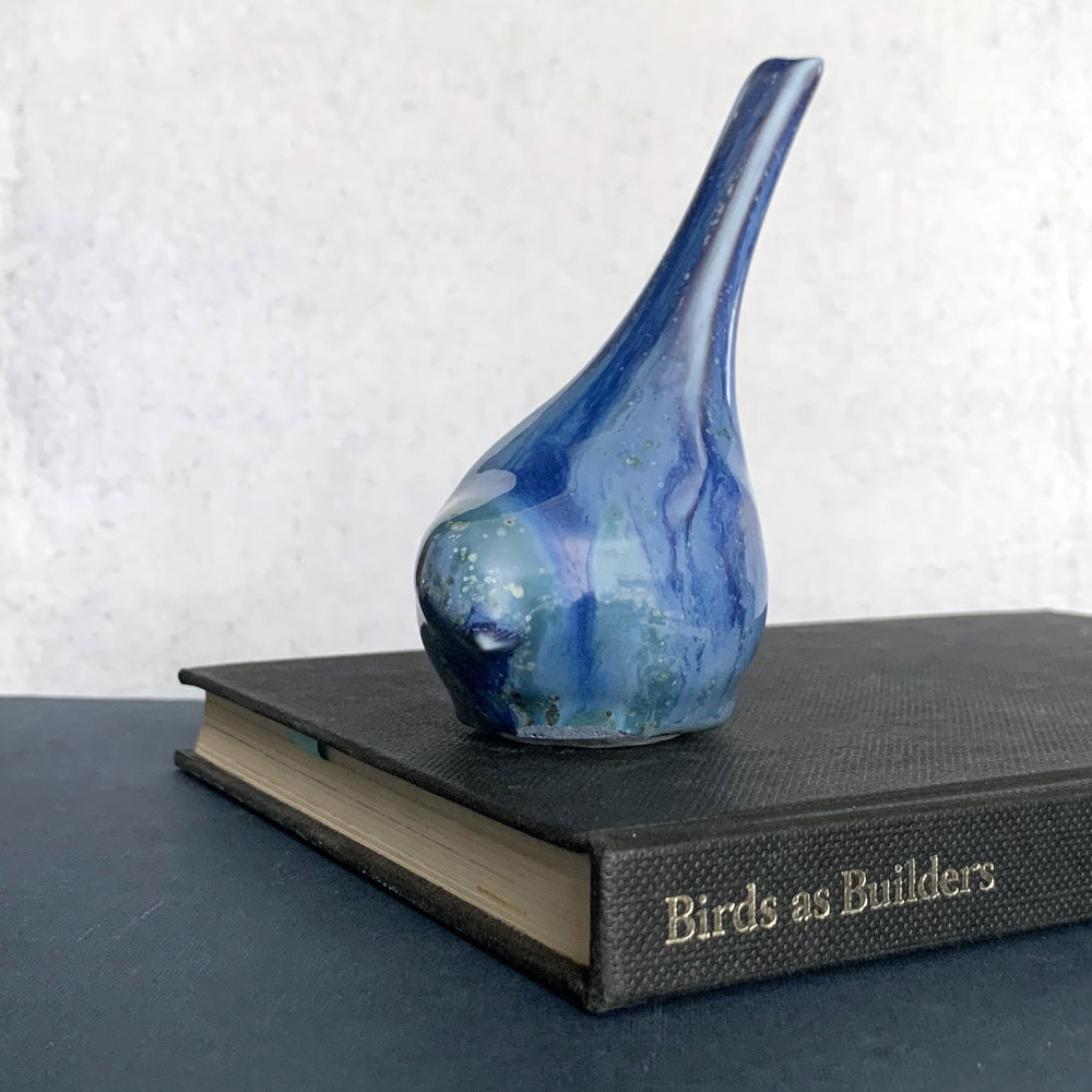 Small, hand sculpted ceramic bird glazed in shiny blues by artist Becky Story. 