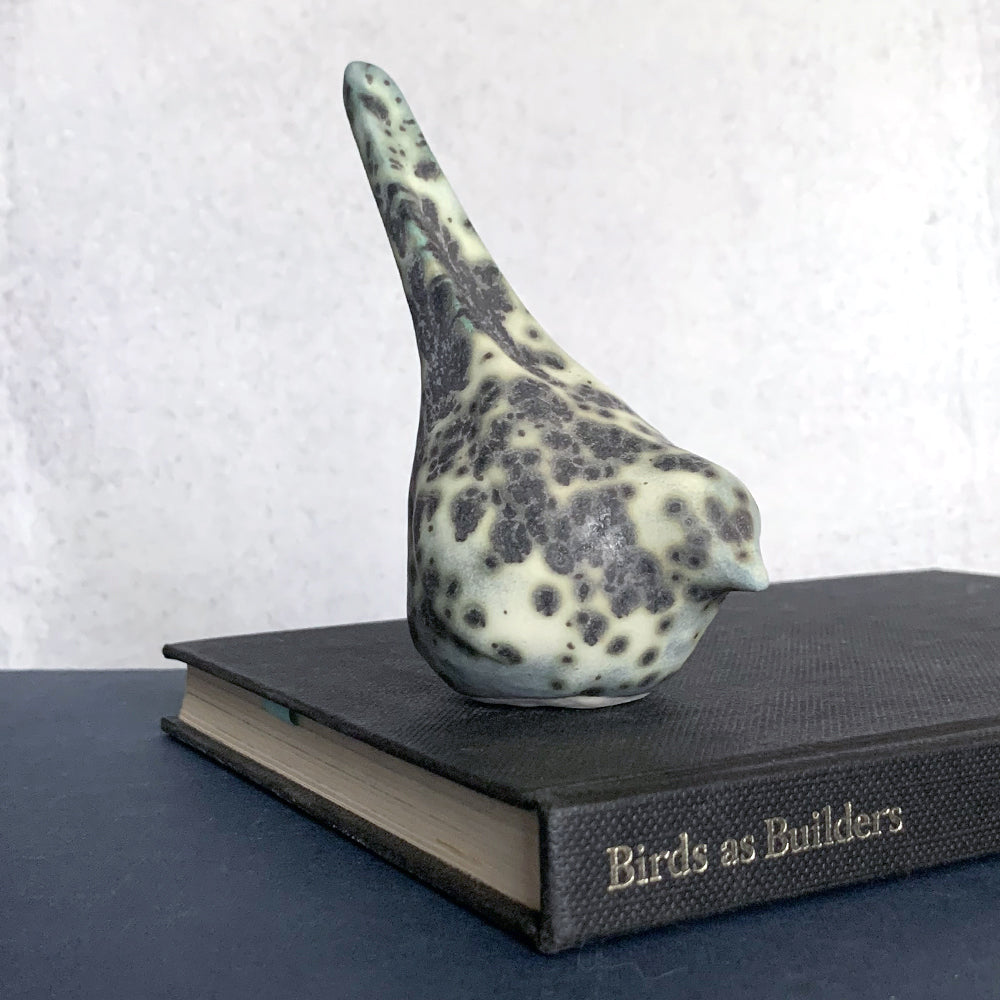 Small, hand sculpted ceramic bird glazed in a cream, pale bluish green and dark gray color by artist Becky Story. 