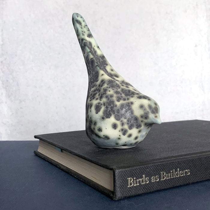 Small, hand sculpted ceramic bird glazed in a cream, pale bluish green and dark gray color by artist Becky Story. 