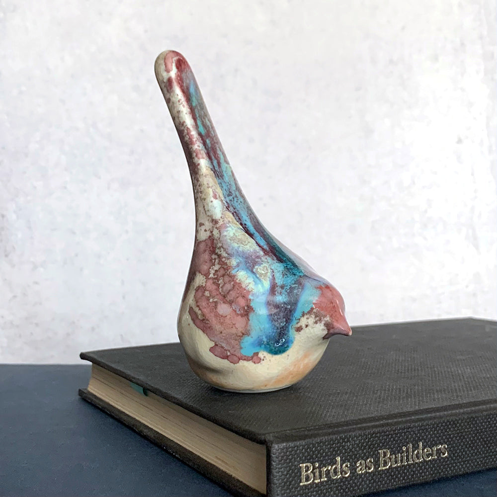 Small ceramic sculpture of a bird, glazed in a rust, cream and blue glaze by artist Becky Story. 