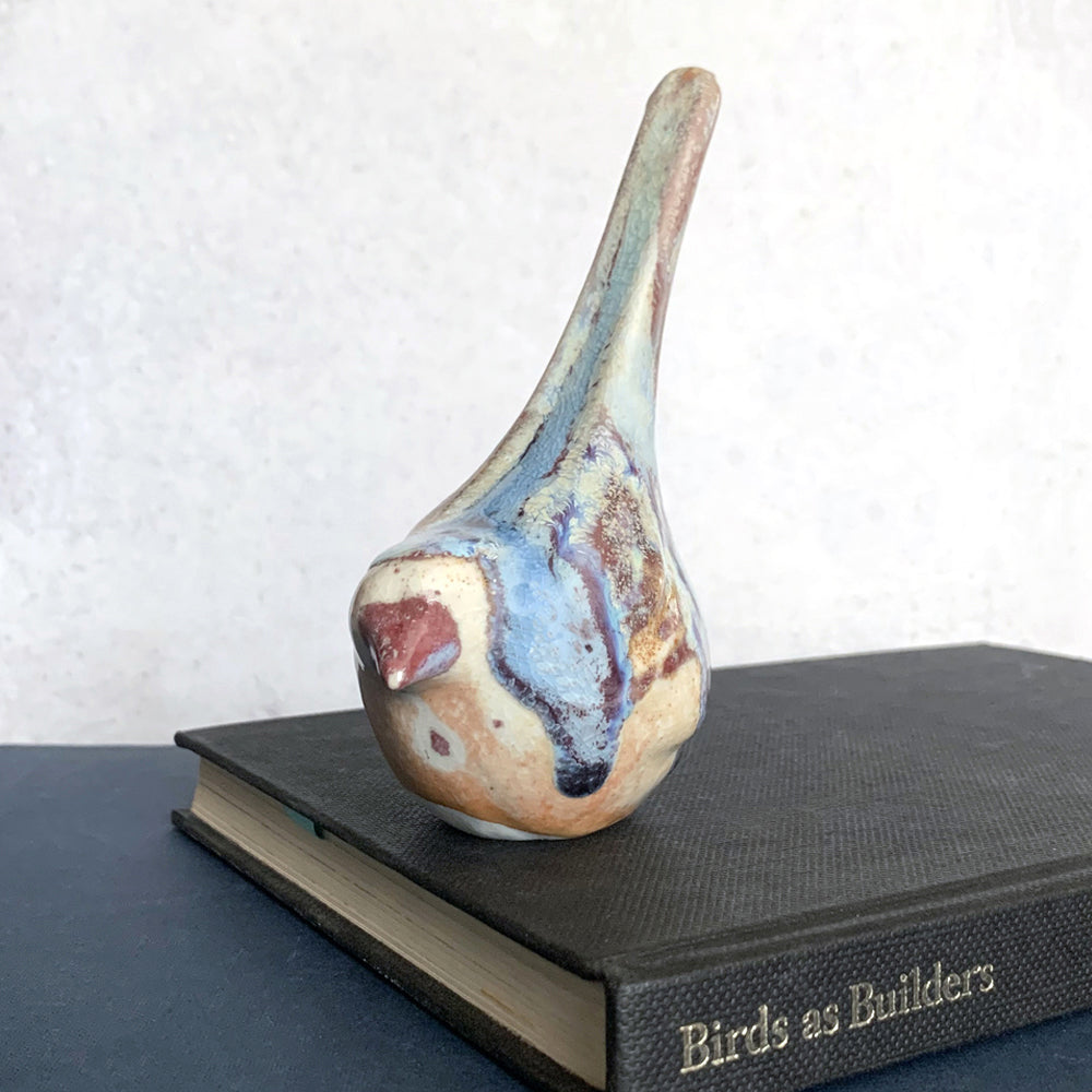 Small ceramic sculpture of a bird, glazed in a rust, cream and blue glaze by artist Becky Story. 